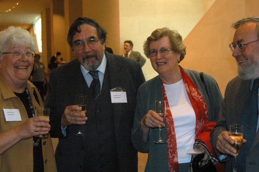 Jill, Robin, Pat and Roger at the launch of the e-learning DVD at the British Museum 2 women and 2 men - Jill, Robin, Pat and Roger - standing in a row holding champagne glasses. They are standing in a large hall and behind them are other attendees at the event.