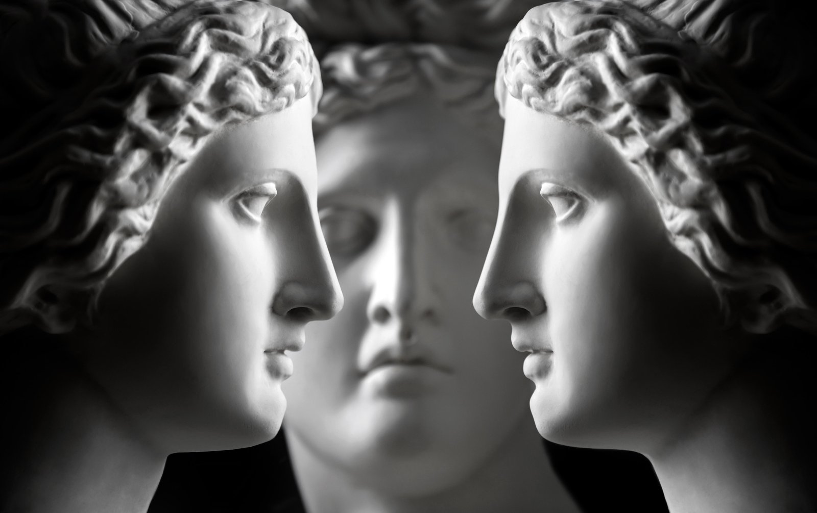 Three marble statue heads (two of Aphrodite and one of Apollo) face each other